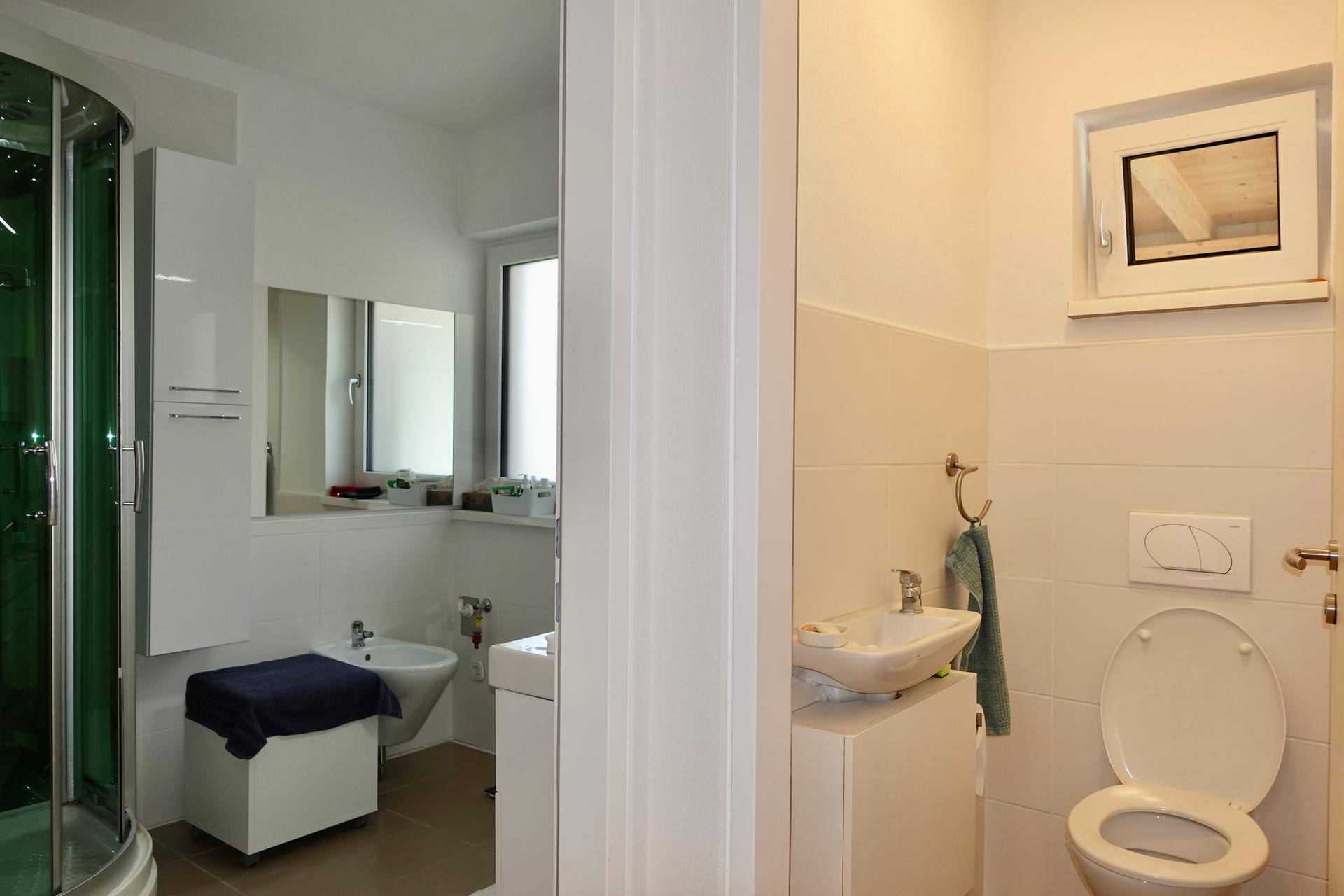 Modernes Badezimmer mit Duschkabine, separatem WC und kleinem Waschbecken.