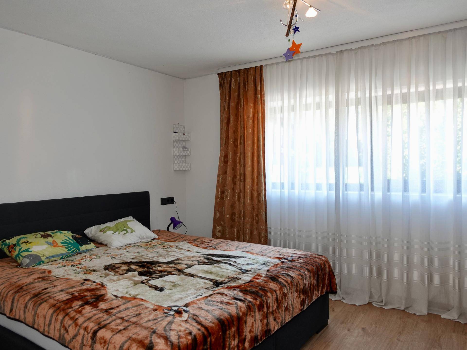 Helles Schlafzimmer mit großem Bett, weißen Wänden und lichtdurchfluteten Fenstern.