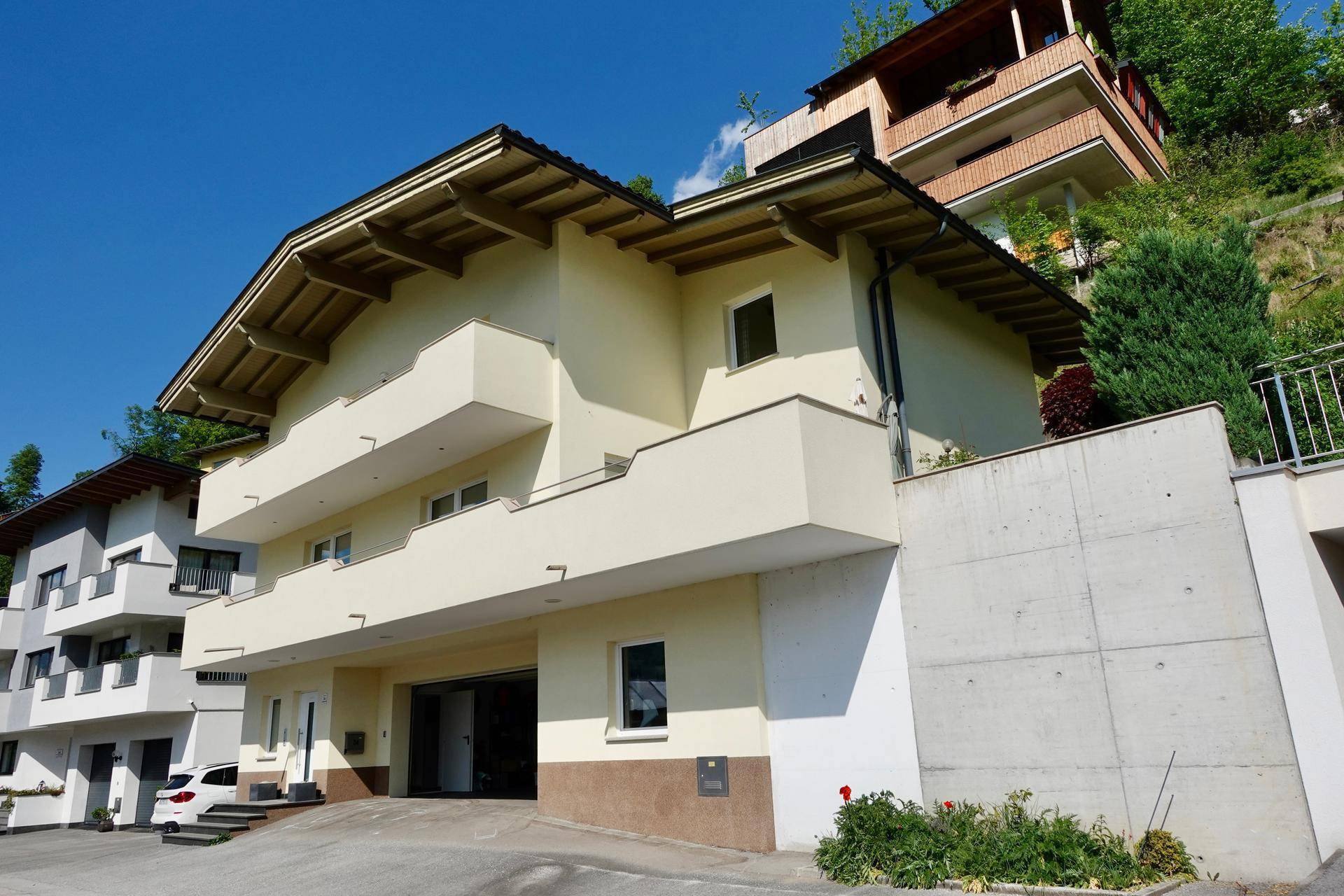 Mehrfamilienhaus mit Balkonen und integrierter Garage in Hanglage.