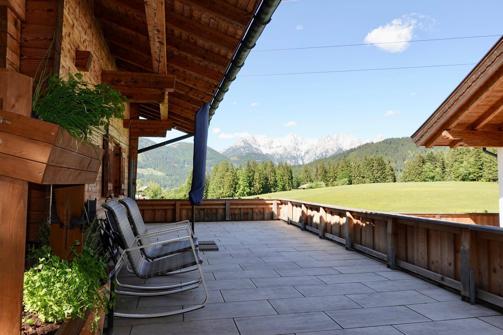 Geräumige Terrasse mit Fliesenboden und Sitzgelegenheiten, bietet einen weiten Bergblick.