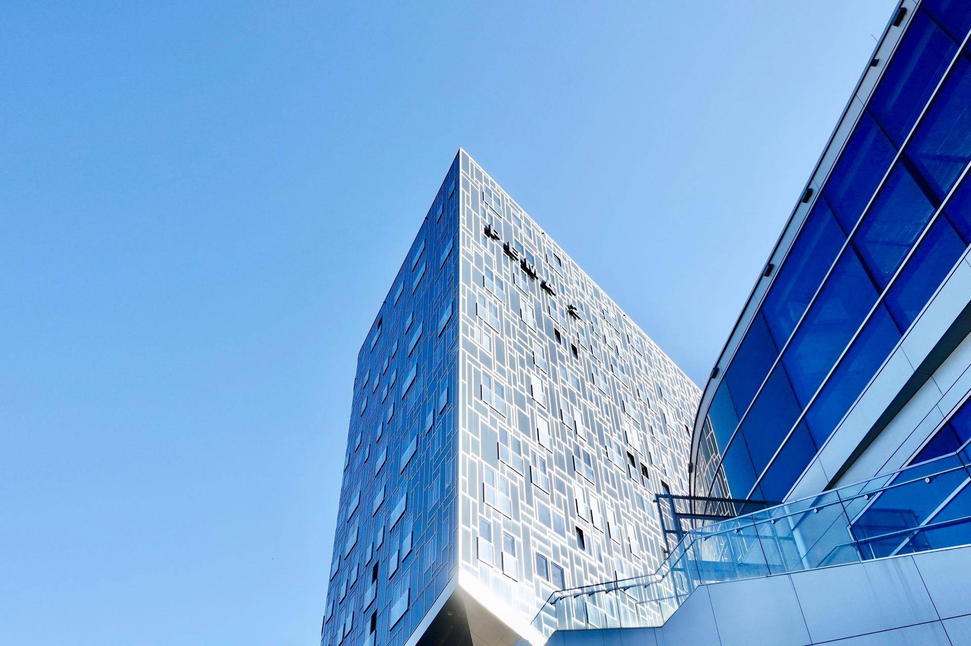 Auffälliges modernes Gebäude mit einer reflektierenden Glasfassade unter einem klaren blauen Himmel.
