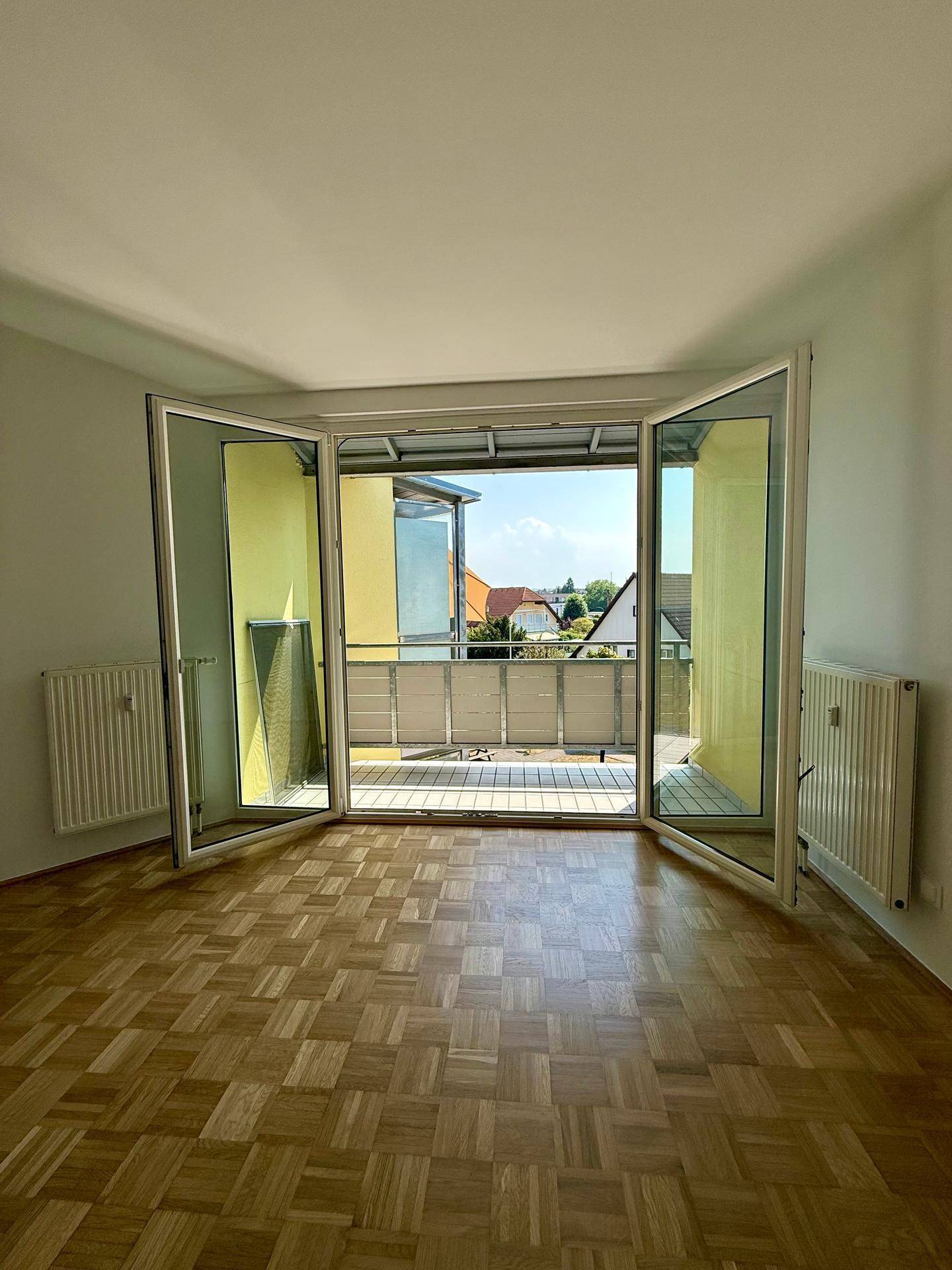 Wohnzimmer mit geöffneten Balkontüren, die einen Blick ins Grüne und viel frische Luft bieten.