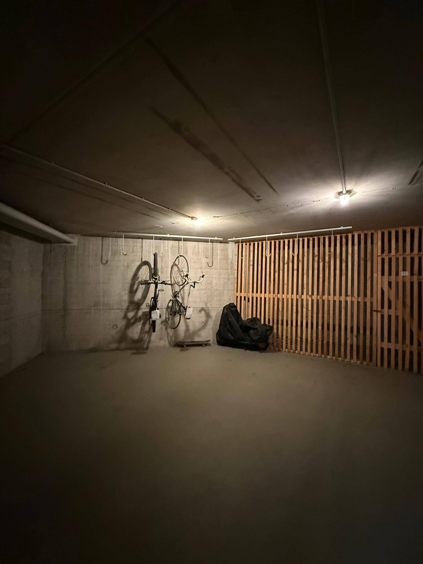 Fahrradraum im Keller mit Betonwänden und Aufhängemöglichkeiten für Fahrräder.