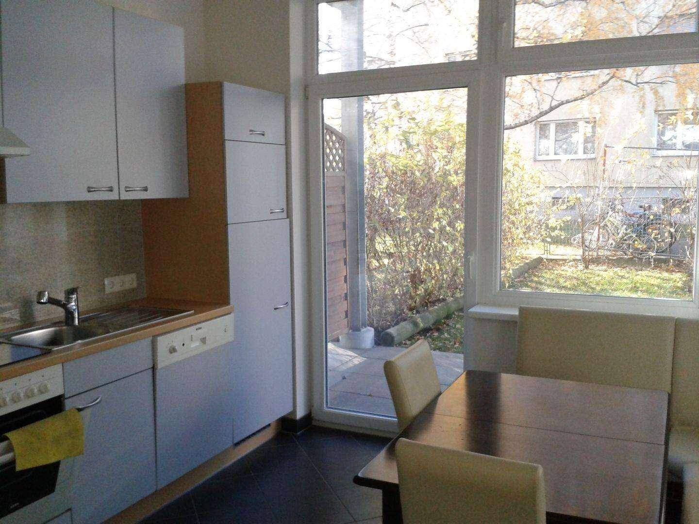 Funktionale Küche mit hellgrauen Schränken, Spülmaschine und Essbereich, mit Zugang zum Garten.