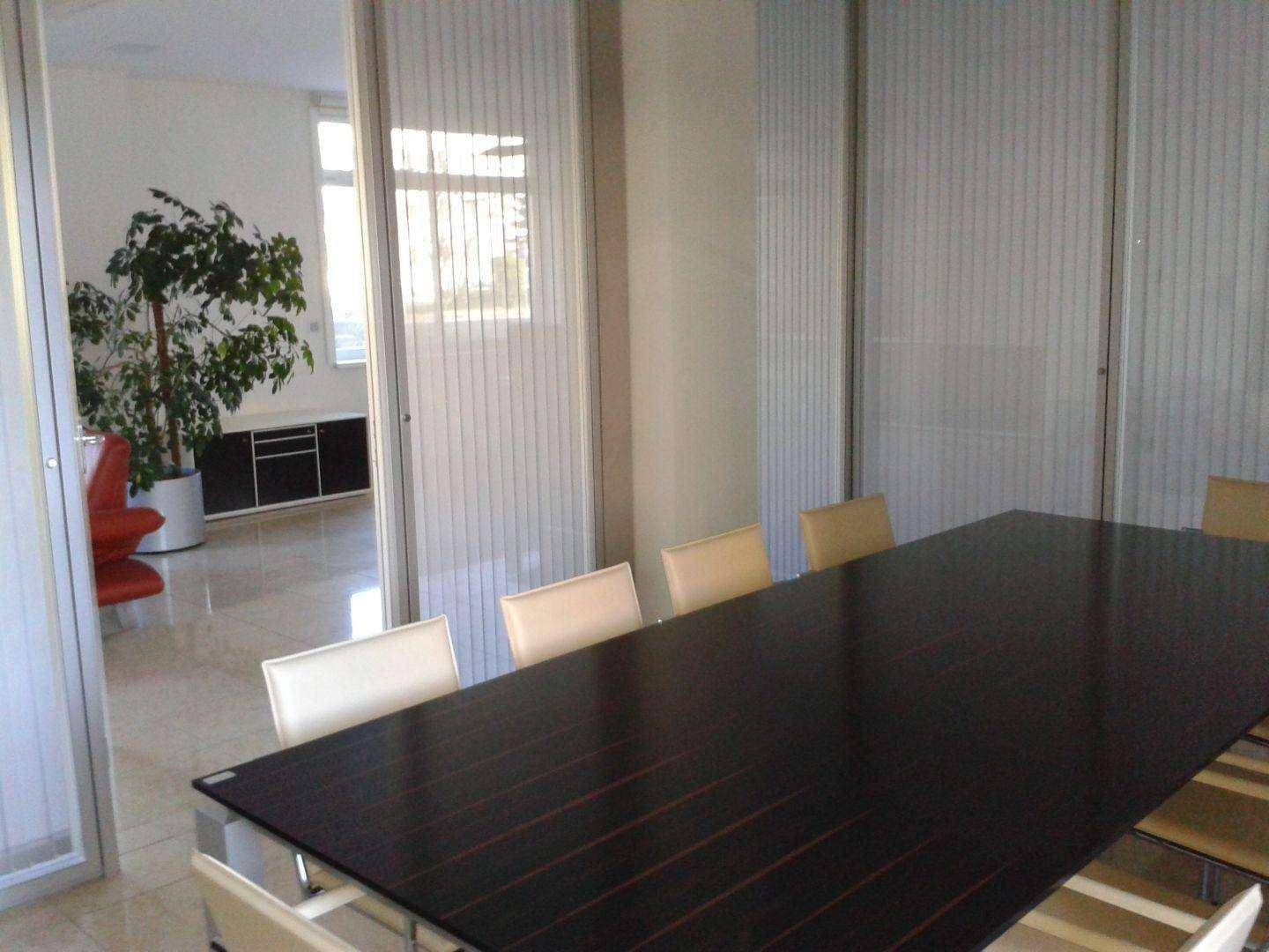 Konferenzraum mit großem dunklem Tisch und Stühlen, abgetrennt durch moderne Milchglas-Trennwände.