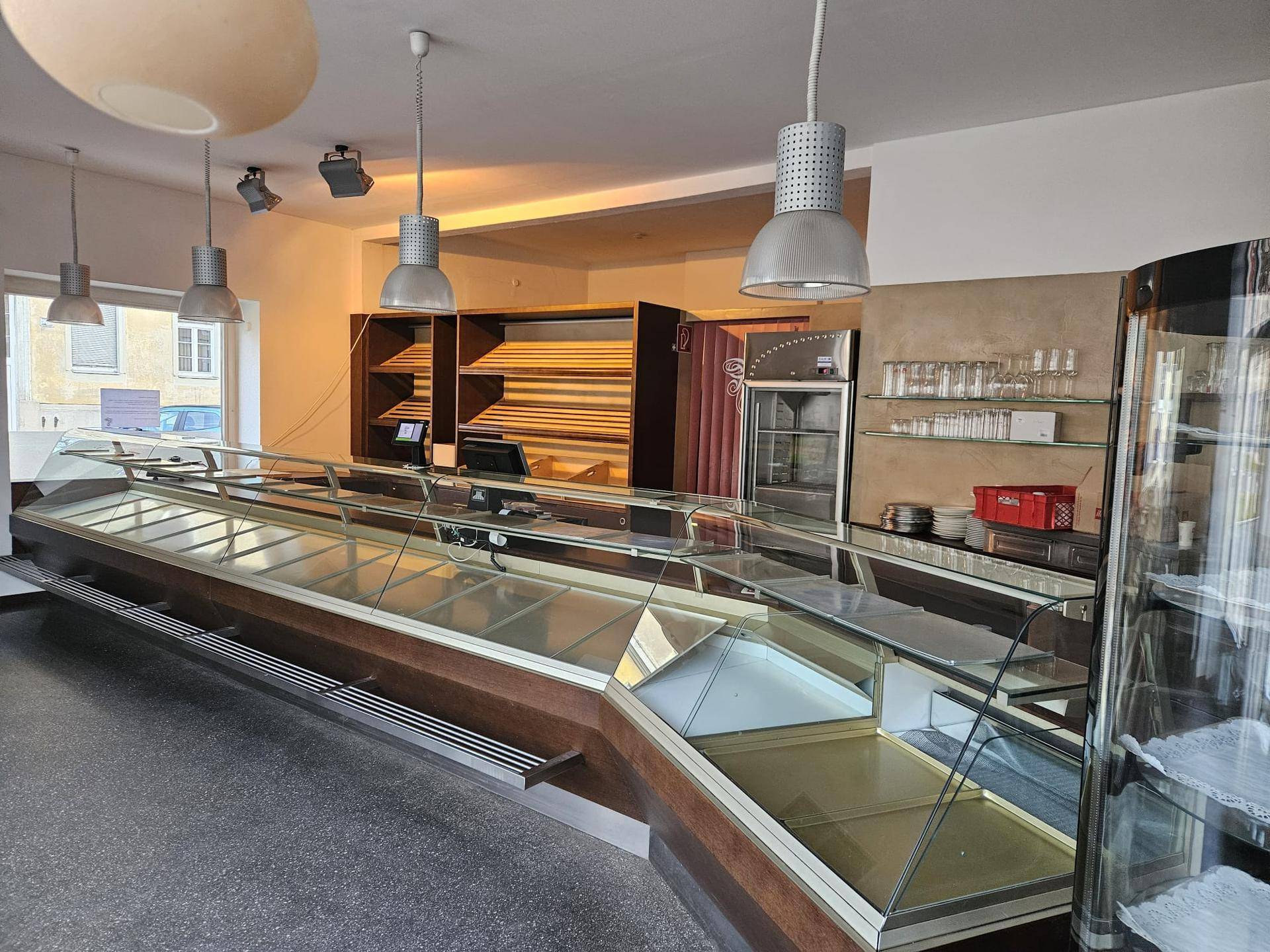 Gewerblicher Verkaufsraum mit langen Theken, Vitrinen und Regalen, ideal für Bäckerei oder Feinkostgeschäft.