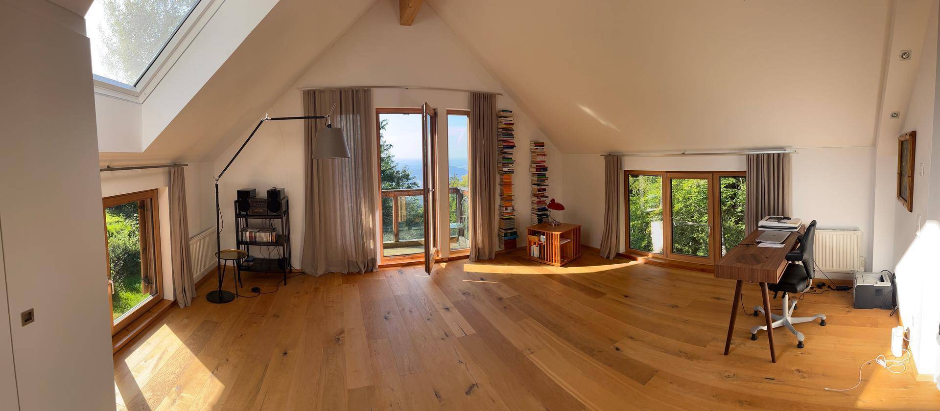 Weitläufiges Dachgeschoss mit Arbeitsbereich, Holzboden und großen Fenstern für viel Licht.