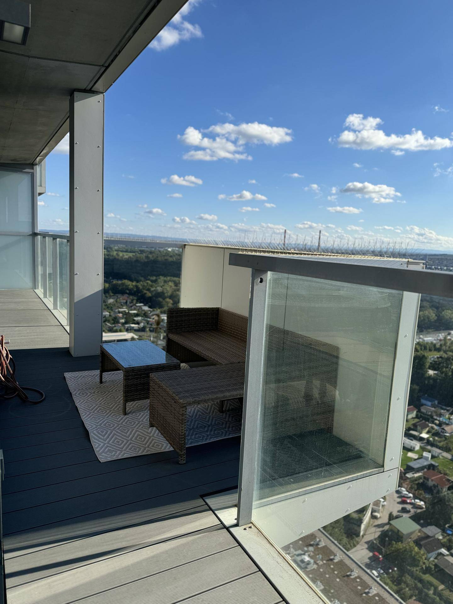 Geräumiger Balkon mit Outdoor-Sitzgelegenheiten und weitem Ausblick auf die Stadt und Landschaft.