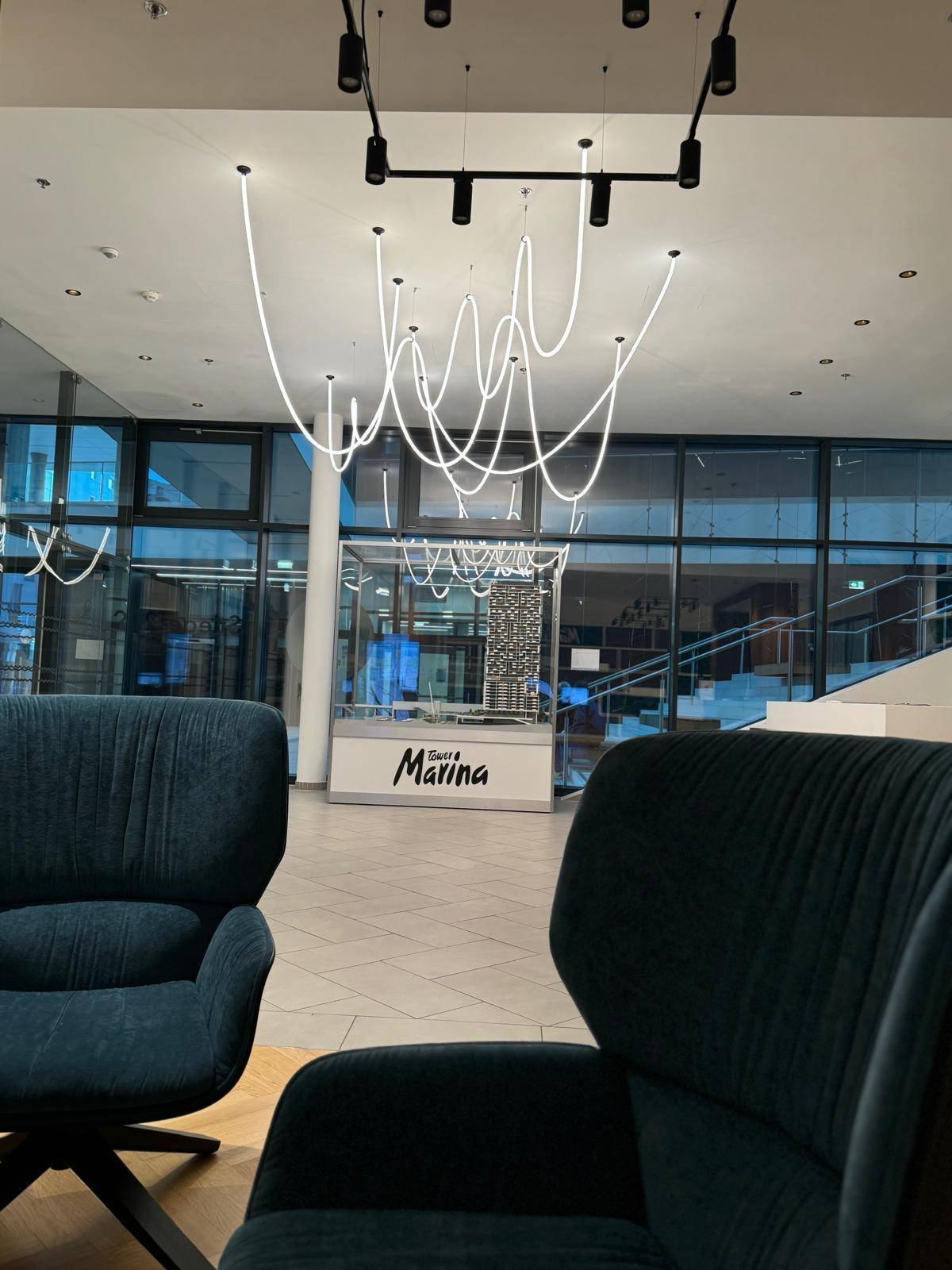 Moderne Lobby mit stilvoller Beleuchtung, Rezeption und großen Glasfronten.