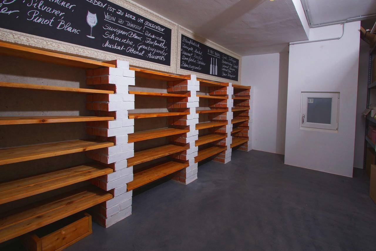 Rustikaler Weinkeller mit Holzregalen und beschreibbaren Tafeln für die Weinsammlung.