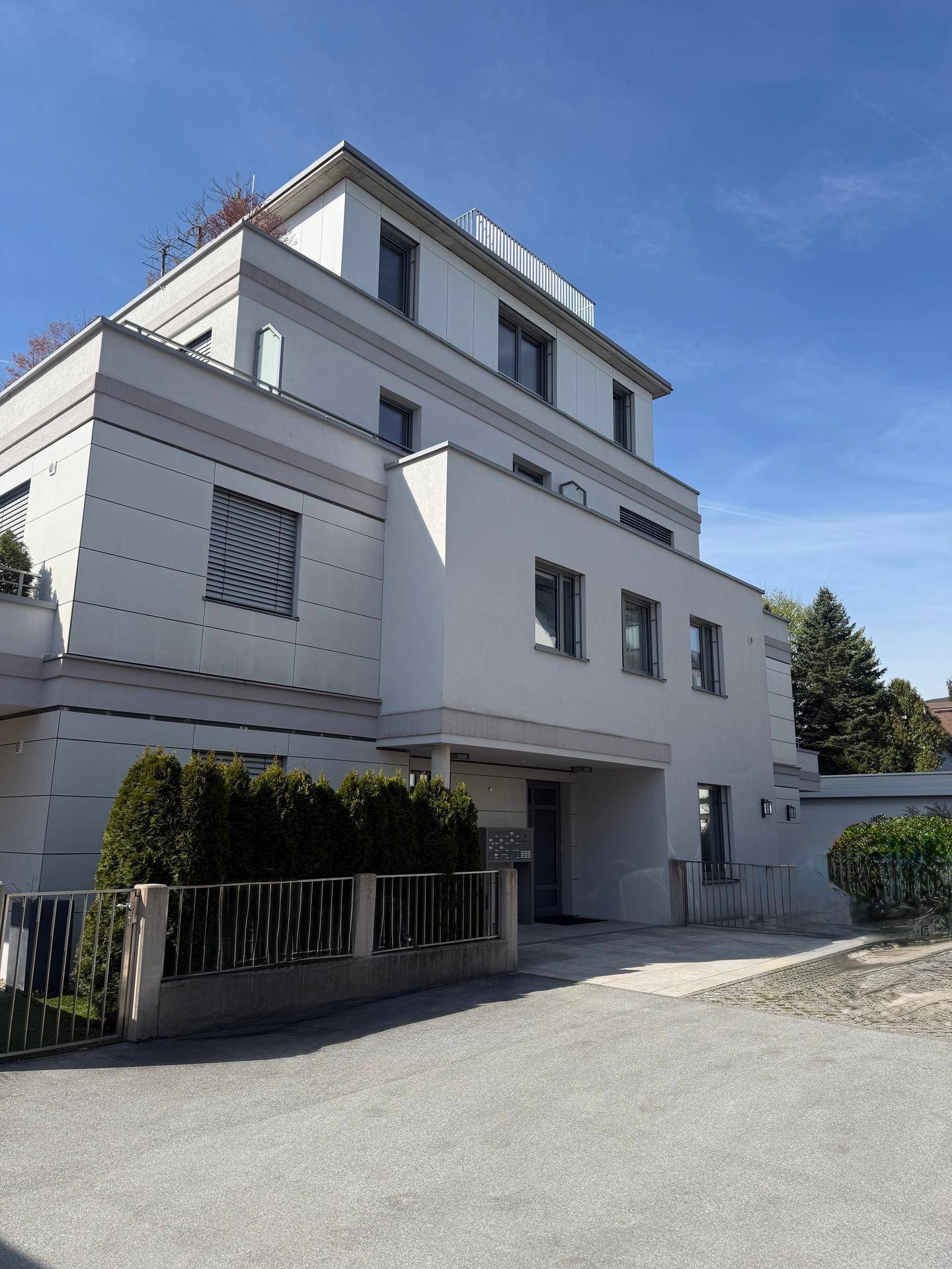 Moderne Stadtvilla mit mehreren Etagen, Flachdach und großen Fenstern in einer gepflegten Umgebung.