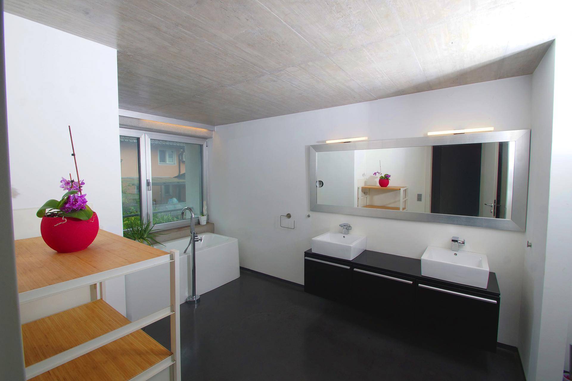 Modernes Badezimmer mit Doppelwaschbecken, Badewanne und großem Fenster für natürliches Licht.