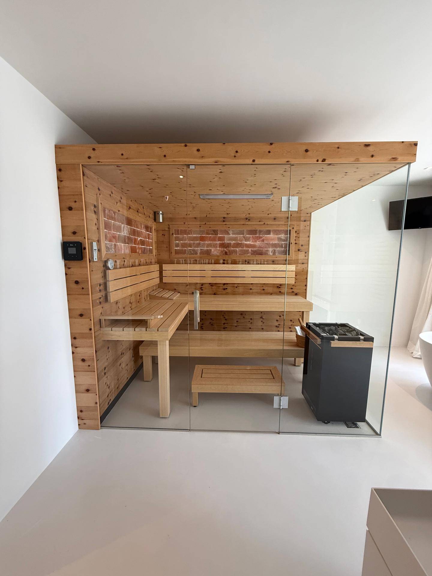 Hochwertige Sauna mit Holzbänken und Glasfront, integriert in ein modernes Badezimmer.