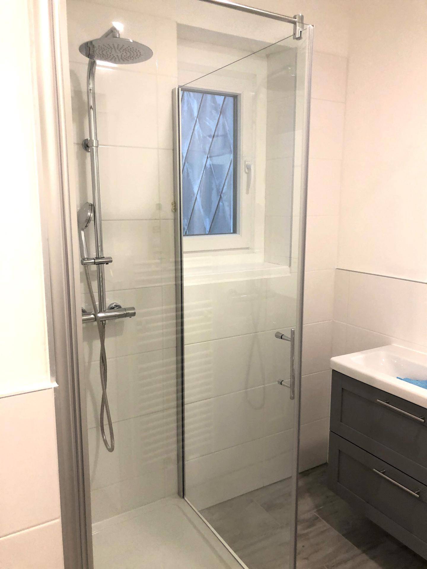 Modernes Badezimmer mit Duschkabine, Regendusche und weißen Fliesen.
