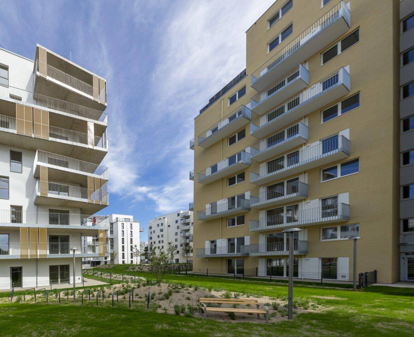 Moderne Wohngebäude mit zahlreichen Balkonen und gepflegten Grünflächen, umgeben von einer ruhigen Wohngegend.