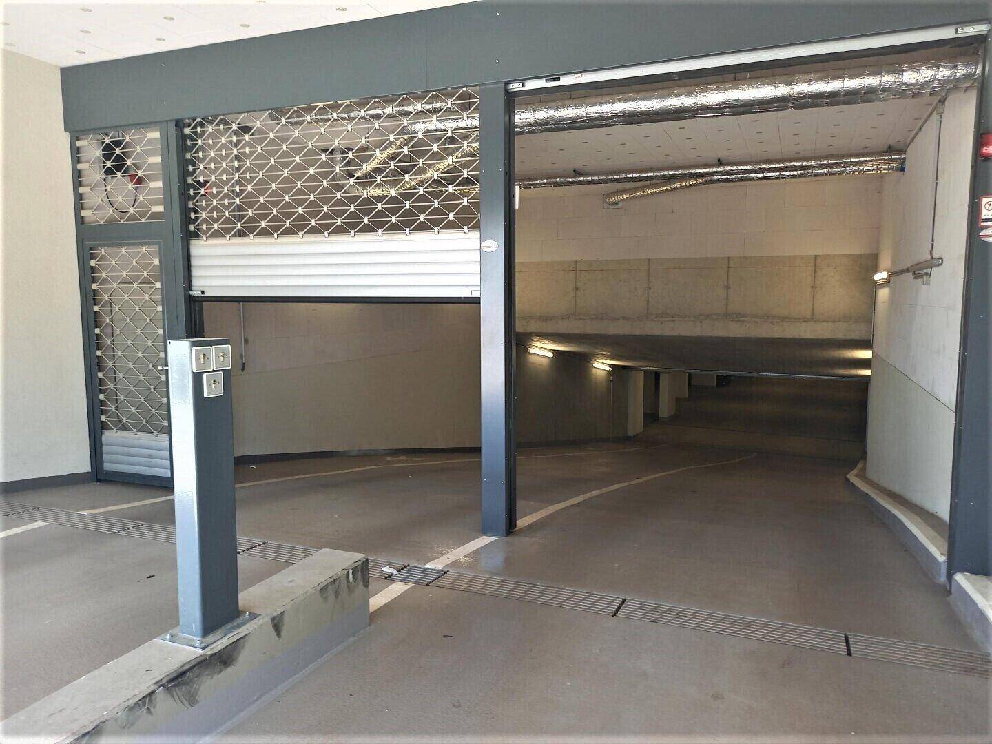 Einfahrt zur Tiefgarage mit Rolltor, Zugangskontrolle und Überwachungskamera.
