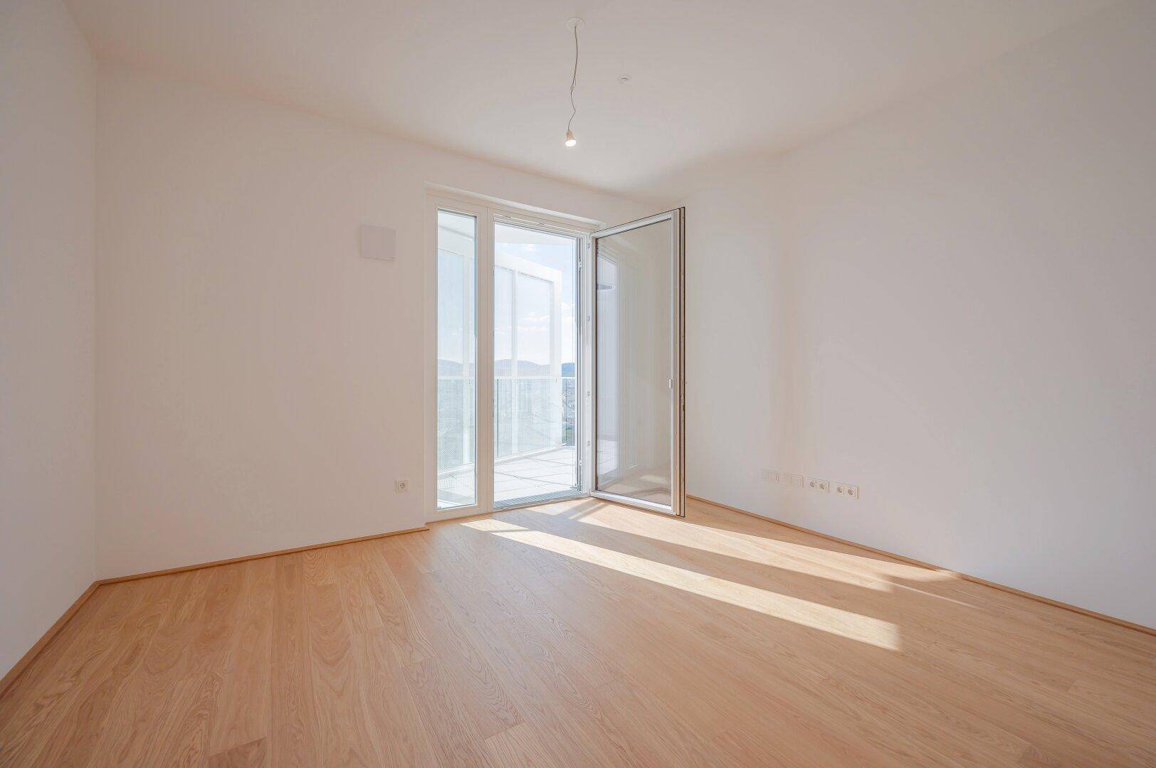 Helles Schlafzimmer mit Holzboden und direktem Zugang zu einem privaten Balkon.