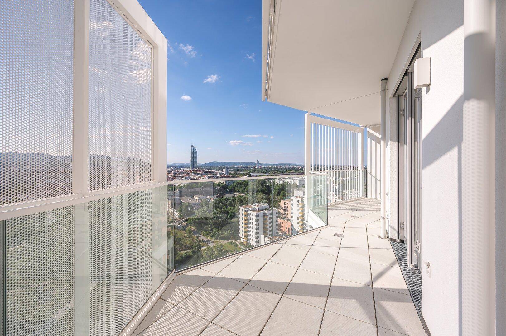 Breiter Balkon mit moderner Glas- und Lochblechbrüstung und weitem Stadtpanorama.
