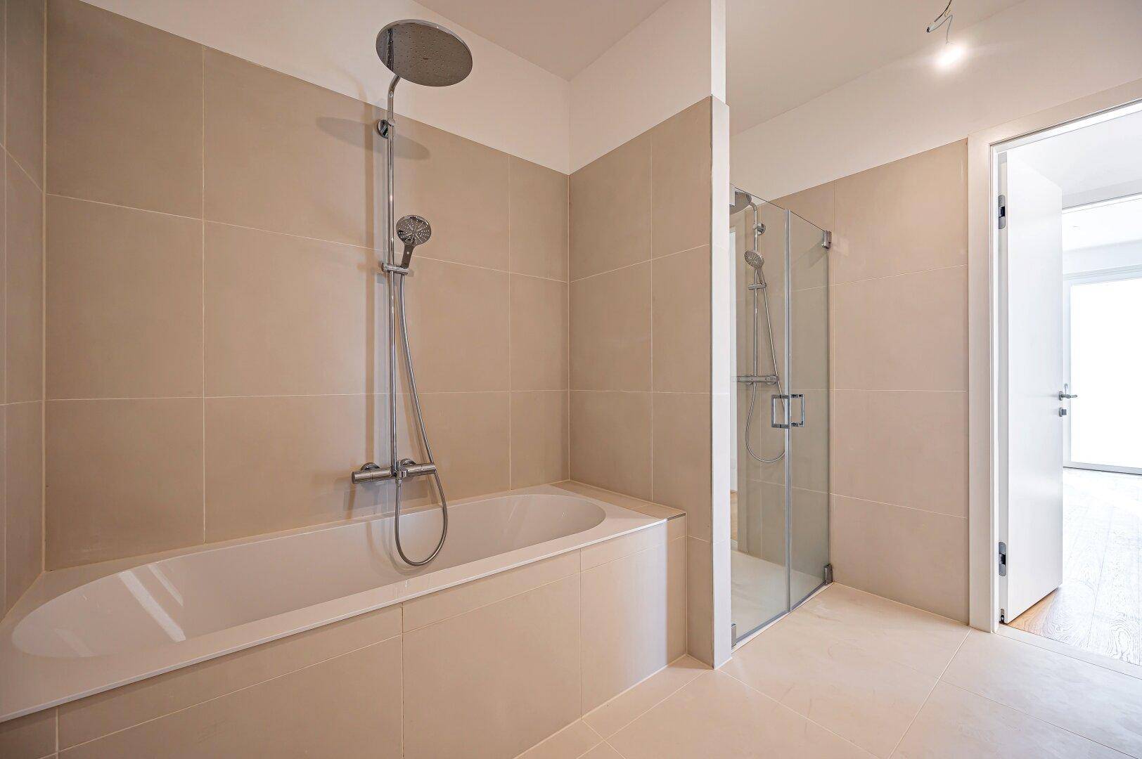 Elegantes Badezimmer mit integrierter Badewanne und separater Glasdusche.