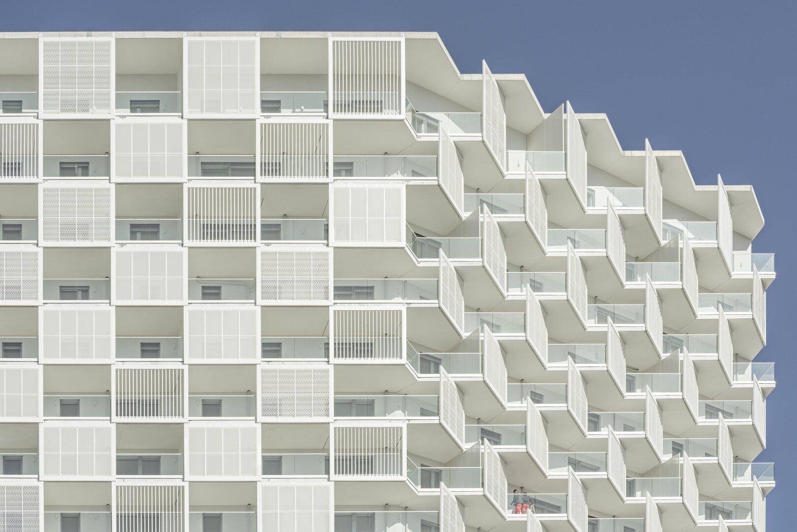 Detailansicht der modernen Fassade mit versetzten Balkonen und filigranen Brüstungen.