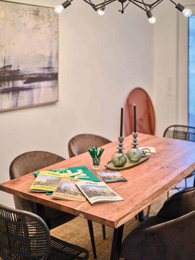 Detailaufnahme des Esstisches mit rustikaler Holzplatte und modernen Stühlen.