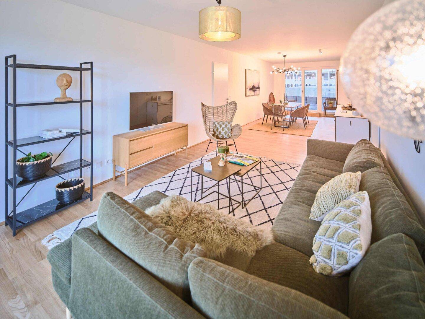 Geräumiger Wohn- und Essbereich mit Parkettboden, modernem Sofa und viel Tageslicht.