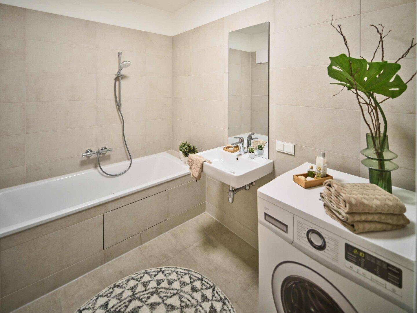 Helles Badezimmer mit Badewanne, Waschmaschine und modernem Waschbecken.