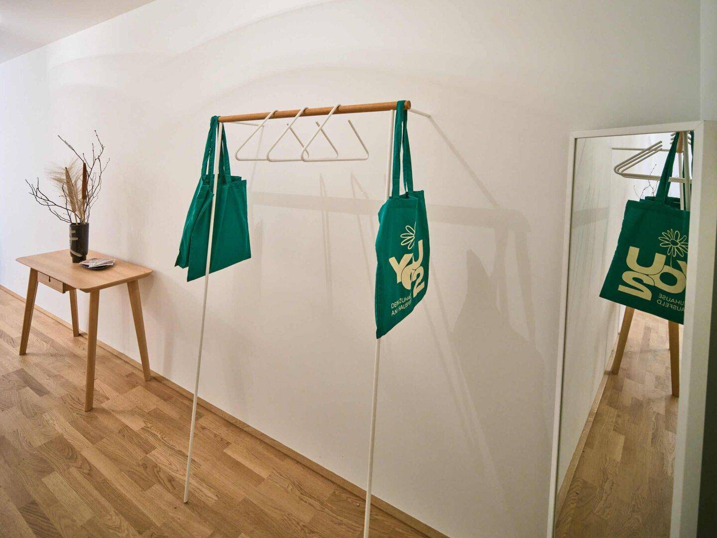 Heller Flur mit Garderobe, Spiegel und Holzboden.