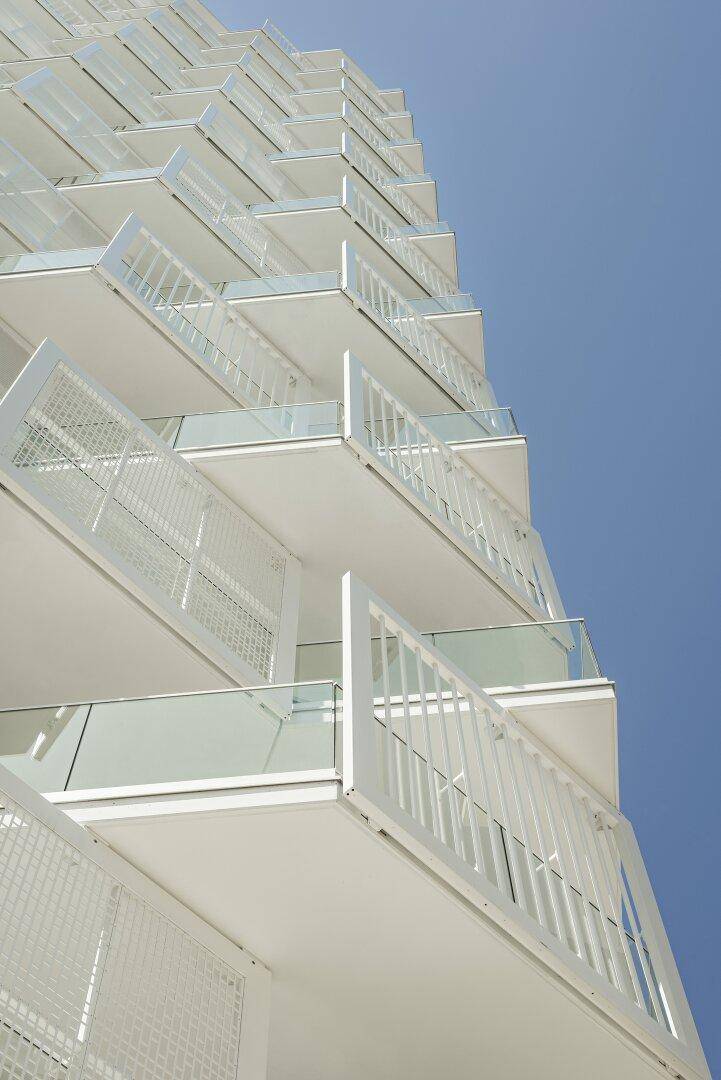 Detailansicht der modernen, gestaffelten Balkone mit Glasgeländern an einem Hochhaus.