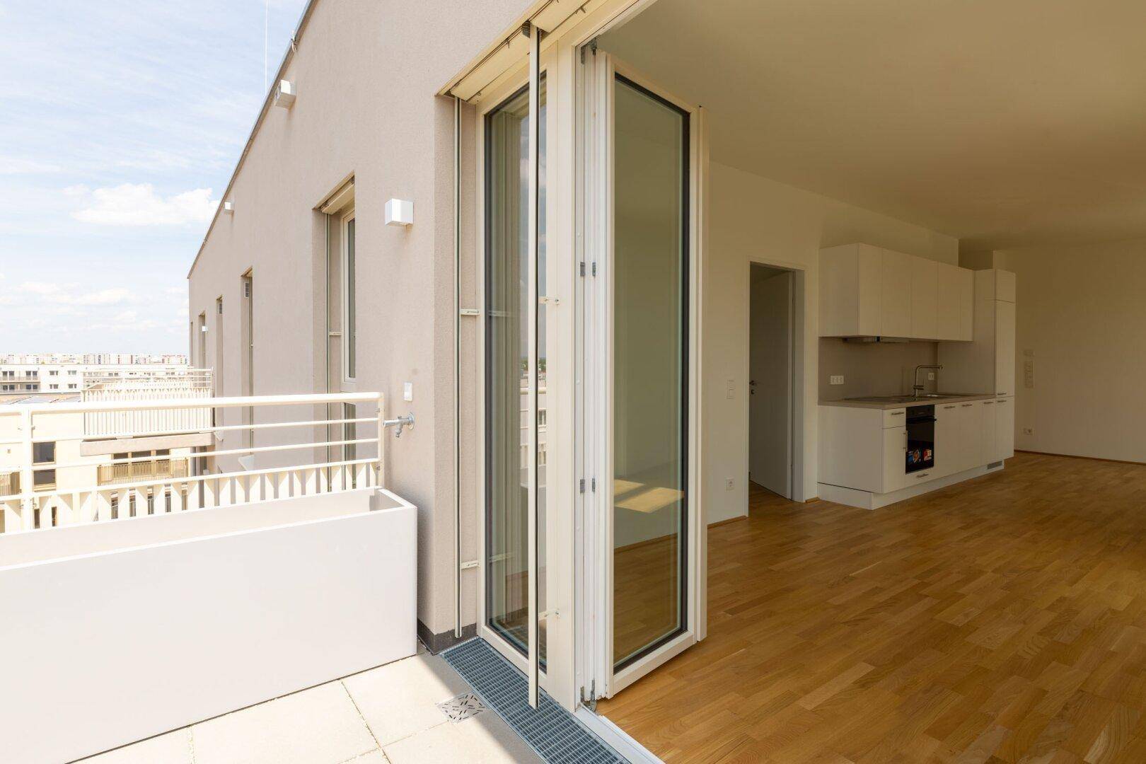 Geräumiger Balkon mit Blick auf die Stadt und direktem Zugang zum hellen Wohnbereich.