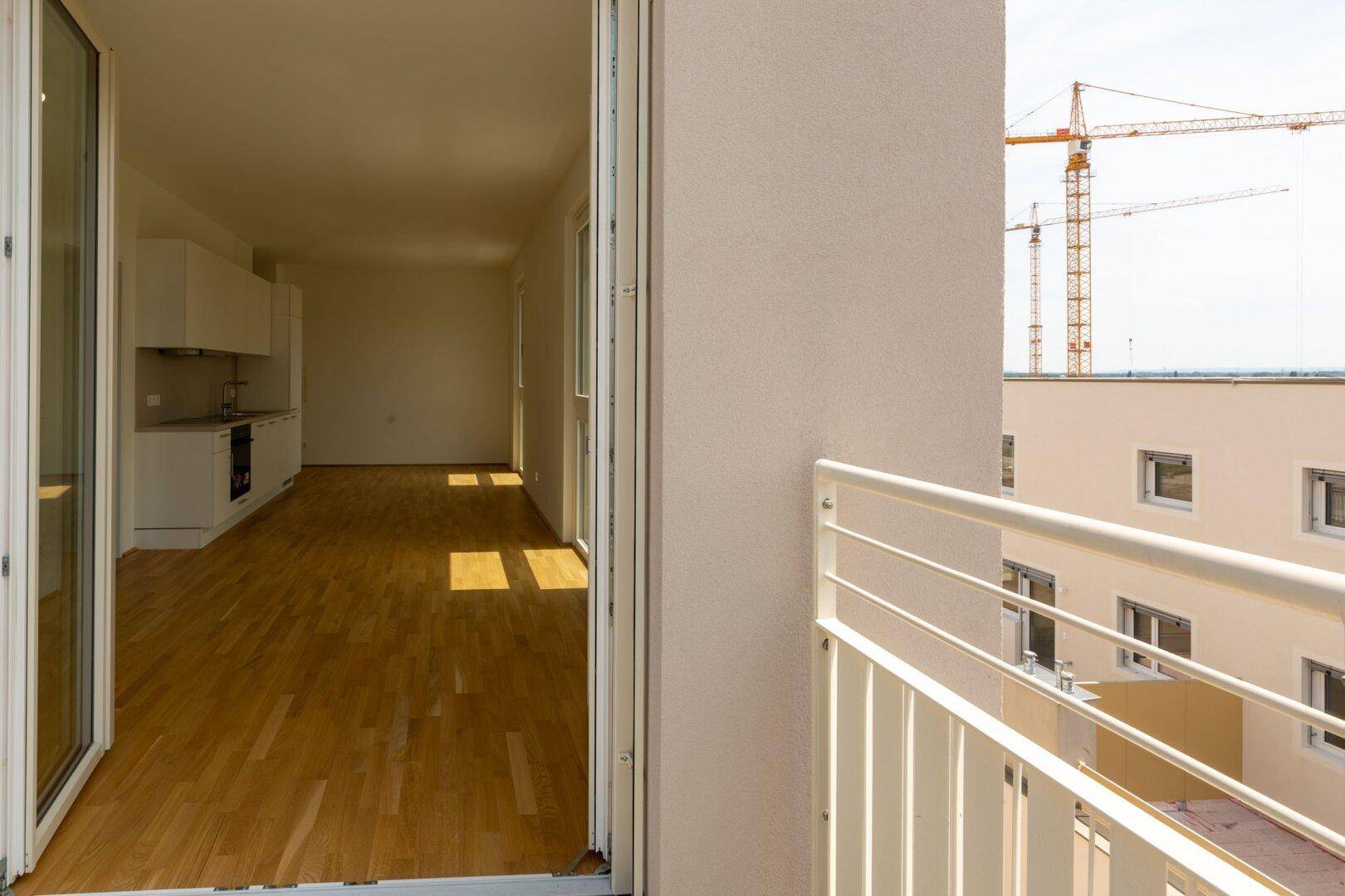 Balkon mit Blick auf die Stadt und Baustellenkräne, der Zugang zum Wohnbereich bietet.