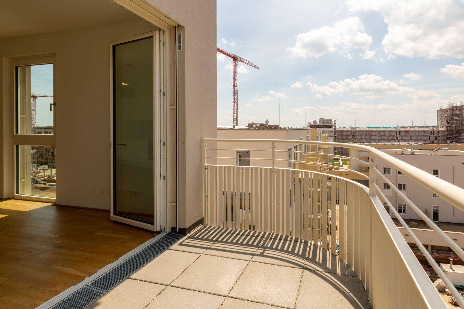 Geschwungener Balkon mit moderner Brüstung und weitem Blick über die städtische Umgebung.