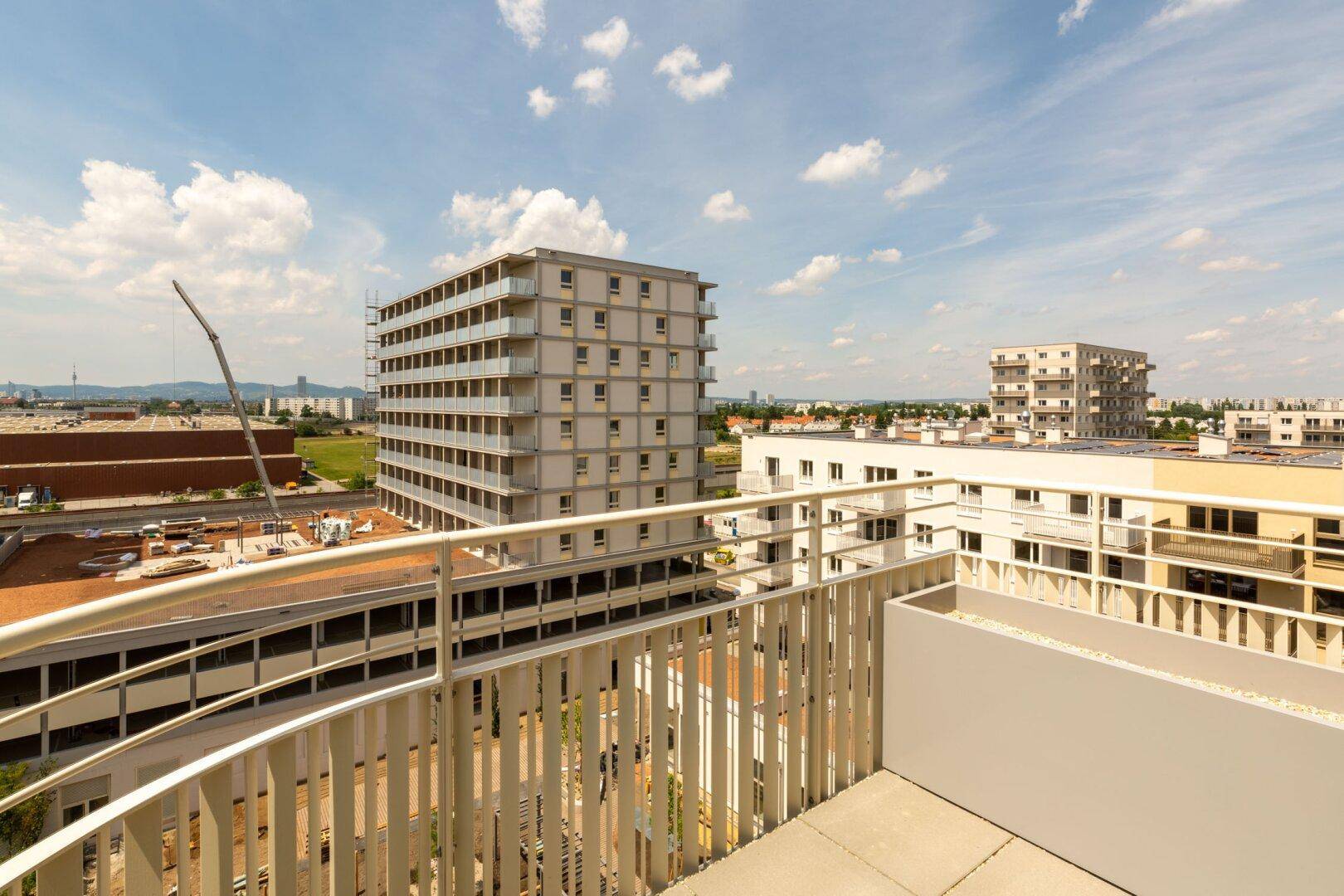 Weiter Ausblick von einem Balkon über die Dächer der Stadt und umliegende Gebäude.