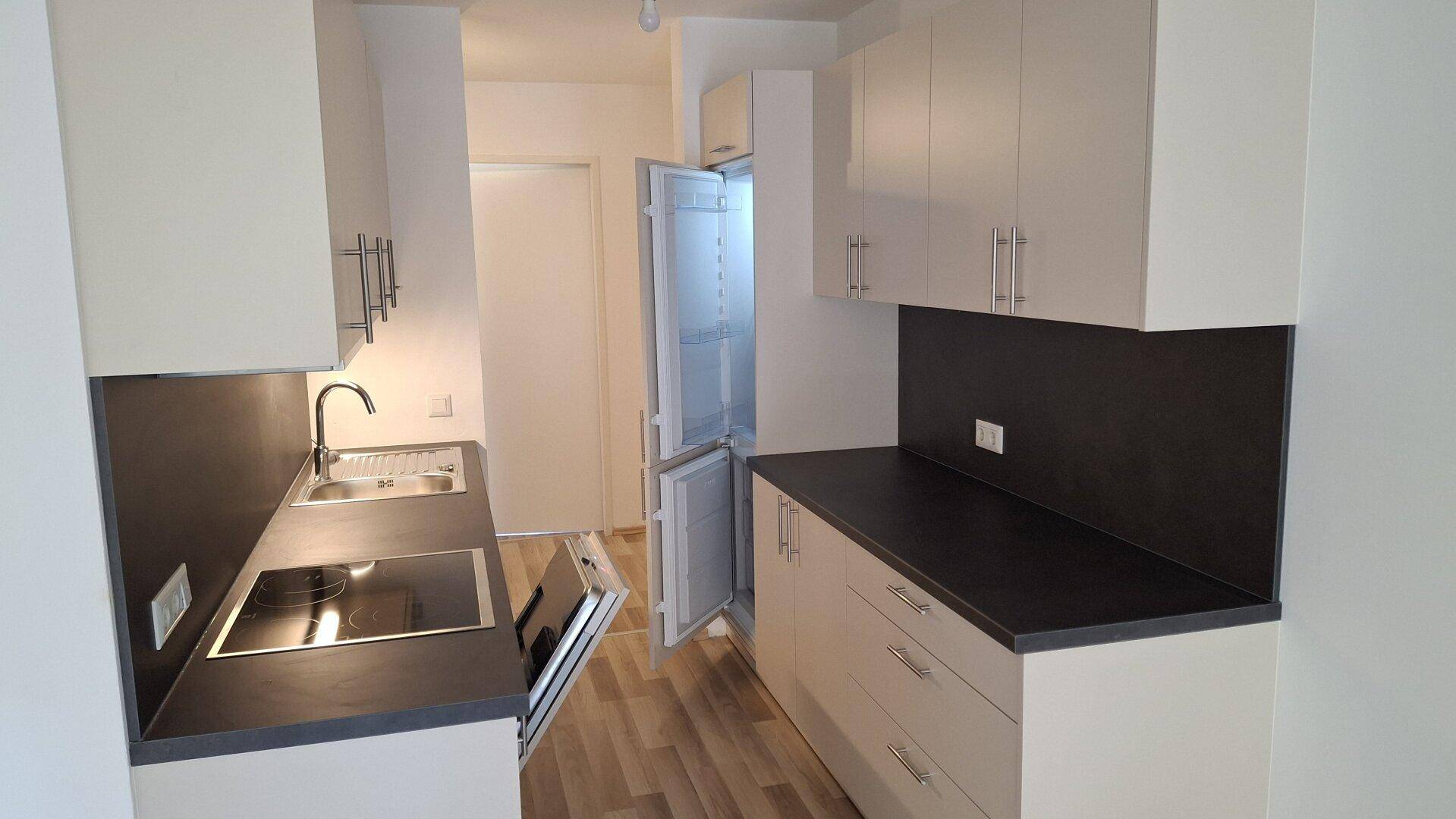 Funktionale Küche mit Einbauschränken, Kochfeld und Kühlschrank, ideal für den täglichen Gebrauch.