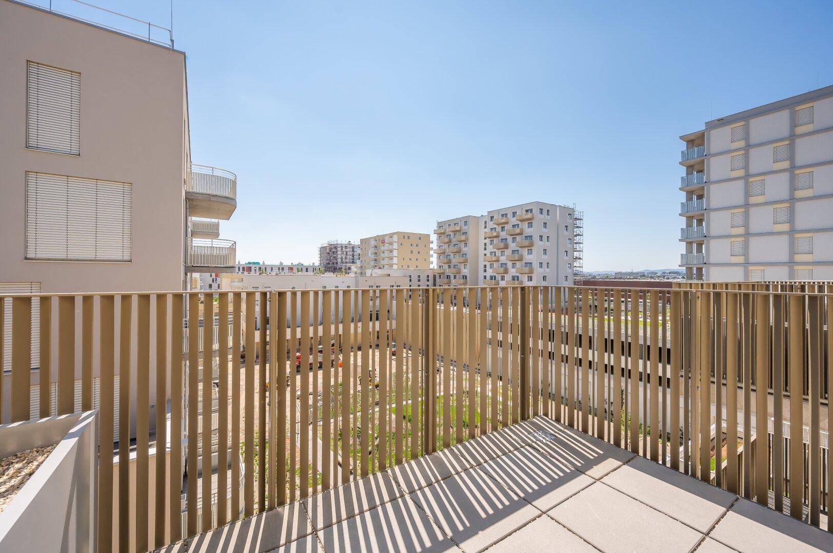 Geräumiger Balkon mit Fliesenboden und modernem Holzgeländer, bietet Blick auf die Umgebung.