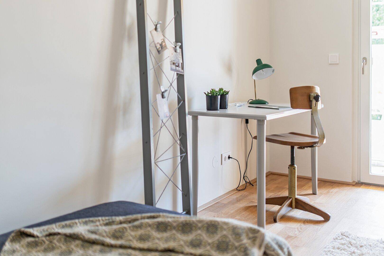 Arbeitsbereich mit Schreibtisch, Stuhl und dekorativer Leiter, ideal für Home-Office-Tätigkeiten.