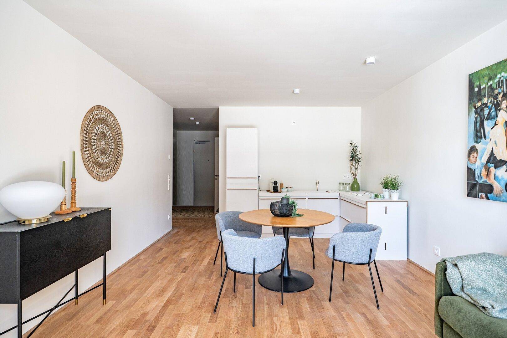 Geräumiger offener Wohn-Essbereich mit Holzboden, moderner Einrichtung und Kunstwerk an der Wand.