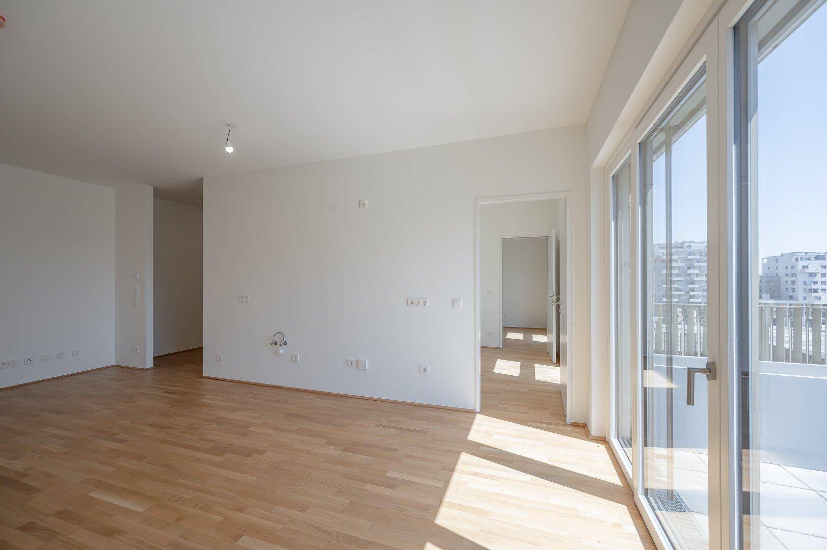 Geräumiges, helles Wohnzimmer mit Parkettboden und großen Schiebetüren zum Außenbereich.
