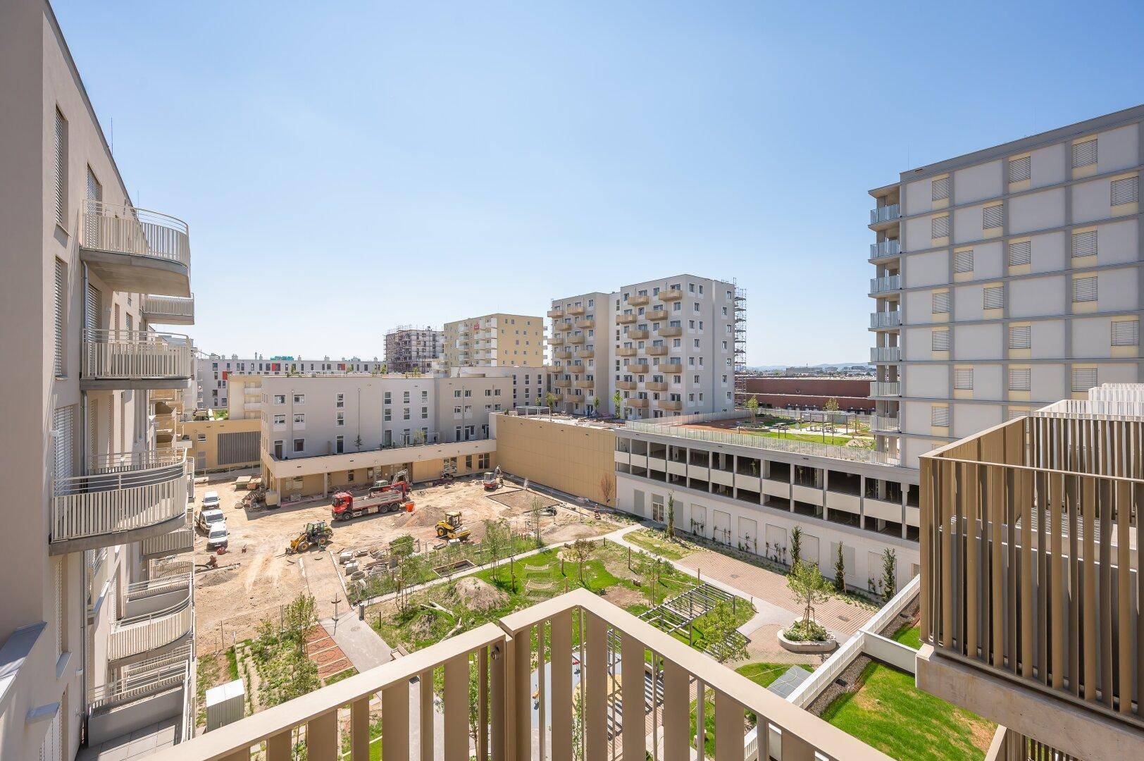 Balkon mit Blick auf die umliegenden Neubauten und eine grüne Innenhofanlage.