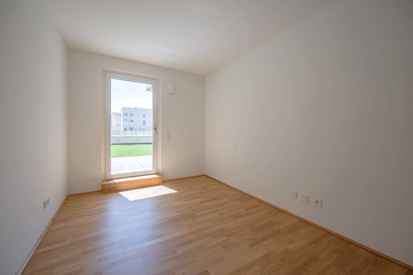 Helles Schlafzimmer mit Parkettboden und direktem Zugang zur Terrasse.