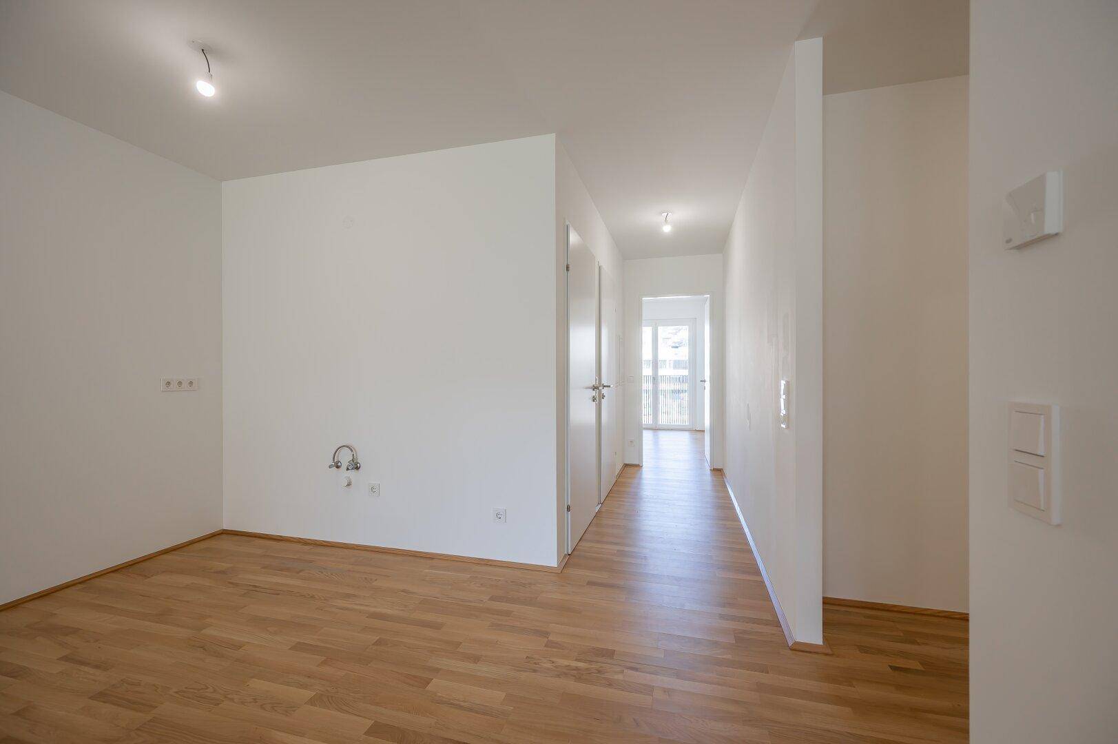 Heller Raum mit Parkettboden und Blick in den angrenzenden Flurbereich.