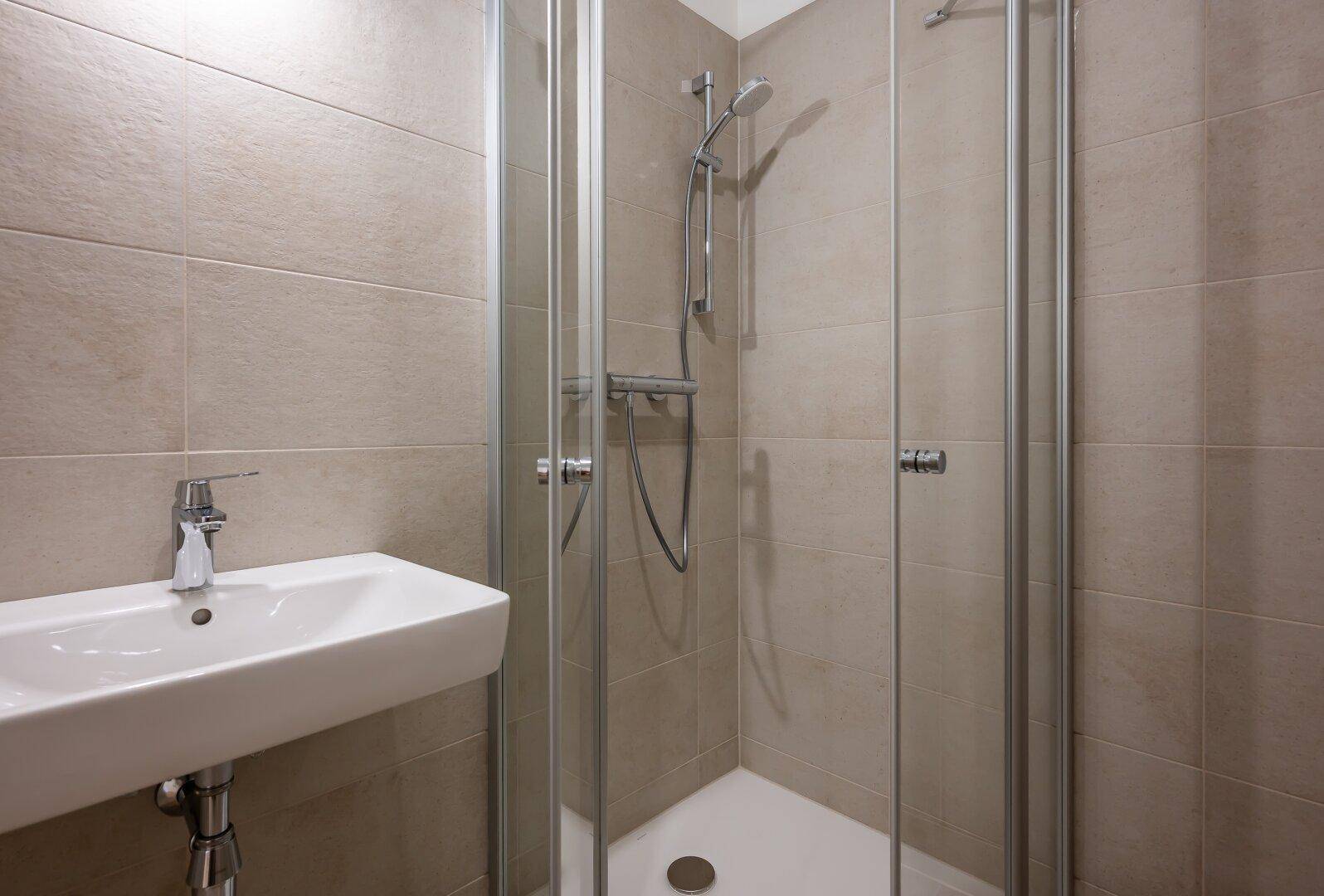 Detaillierte Ansicht der Duschkabine und des Waschbeckens im modernen Badezimmer.