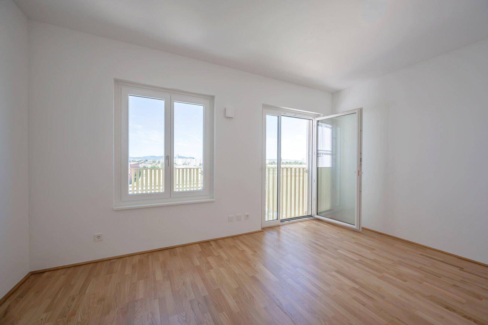 Geräumiges, helles Zimmer mit Holzboden und direktem Zugang zu einem Außenbereich.