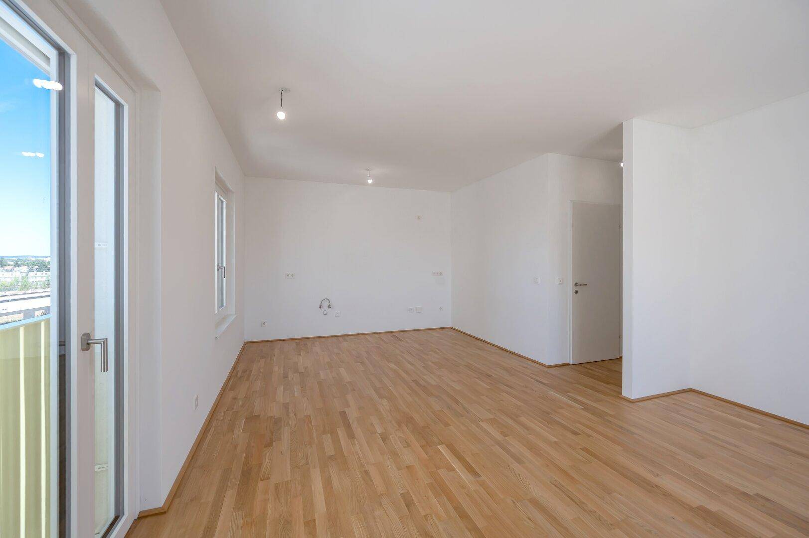 Helles, leeres Zimmer mit Parkettboden und Zugang zu einem Außenbereich, bereit zur individuellen Gestaltung.
