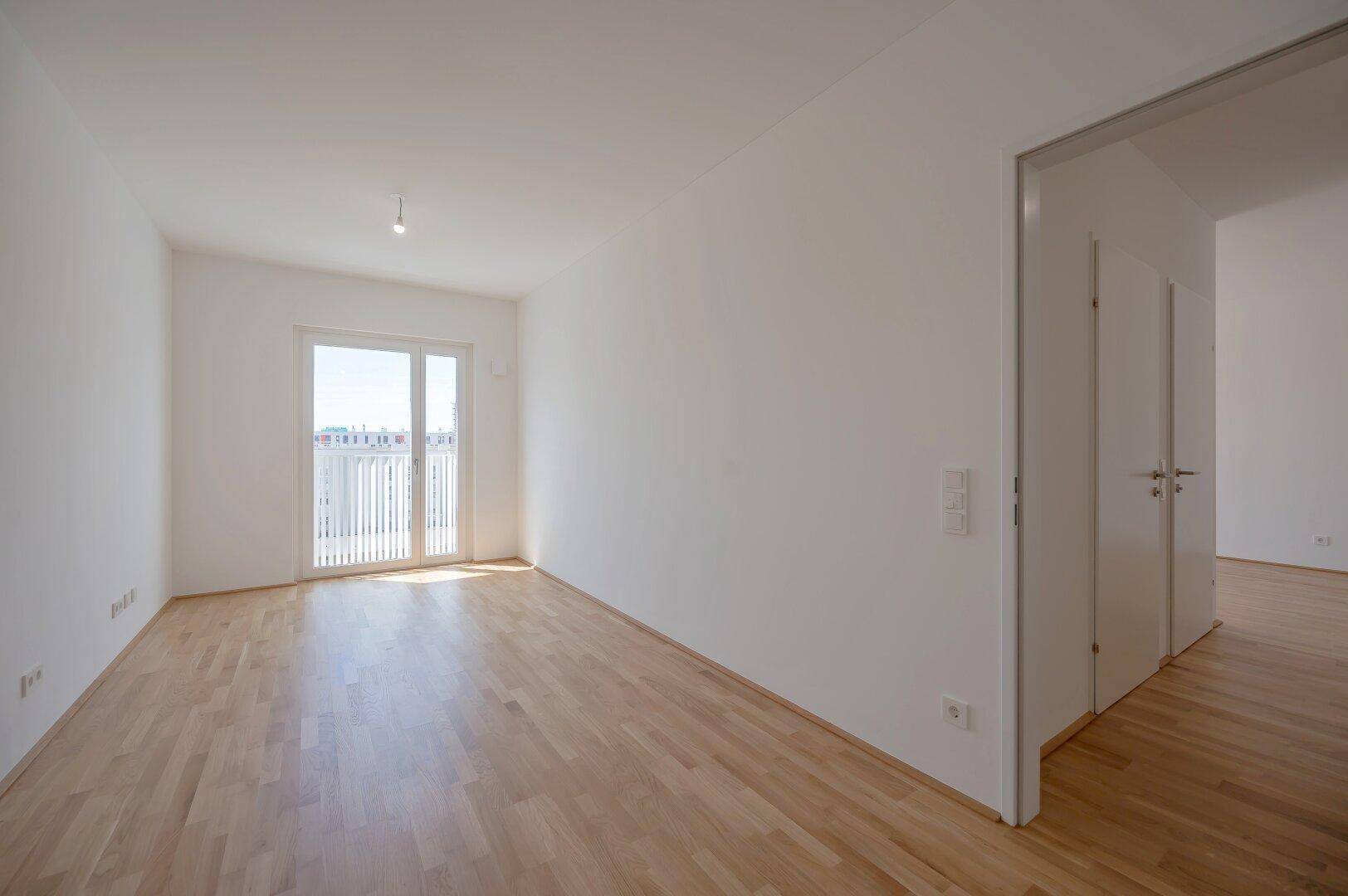 Helles Zimmer mit Holzboden und Zugang zu einem französischen Balkon, ideal für viel Licht.