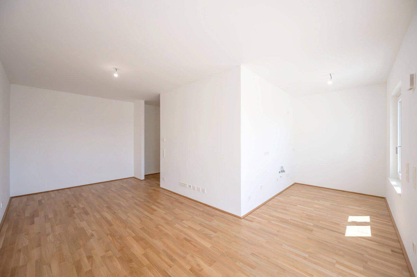 Heller, leerer Raum mit Holzboden und weißen Wänden, bereit zur individuellen Gestaltung.