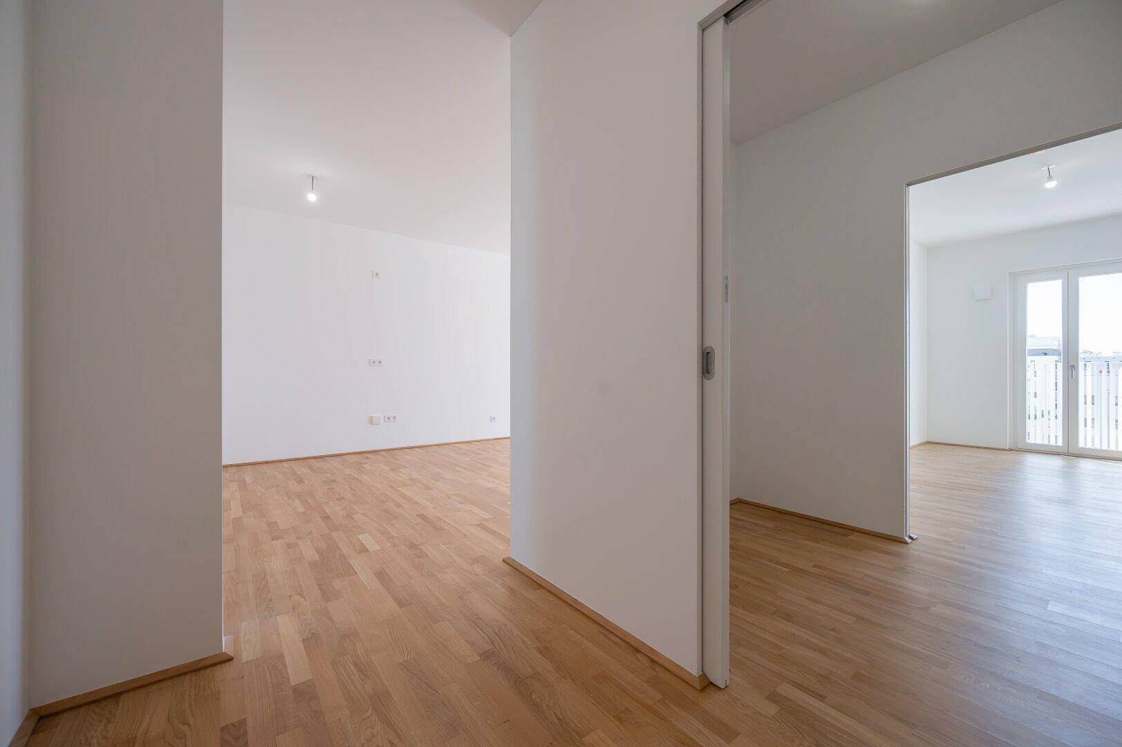 Geräumiger Flur mit Parkettboden, der verschiedene helle Wohnbereiche miteinander verbindet.