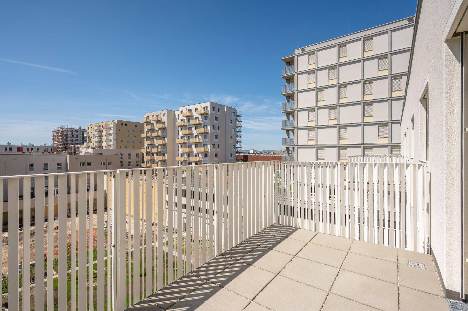 Heller Balkon mit Fliesenboden und vertikalen Lamellen, bietet einen weiten Blick auf die Umgebung.