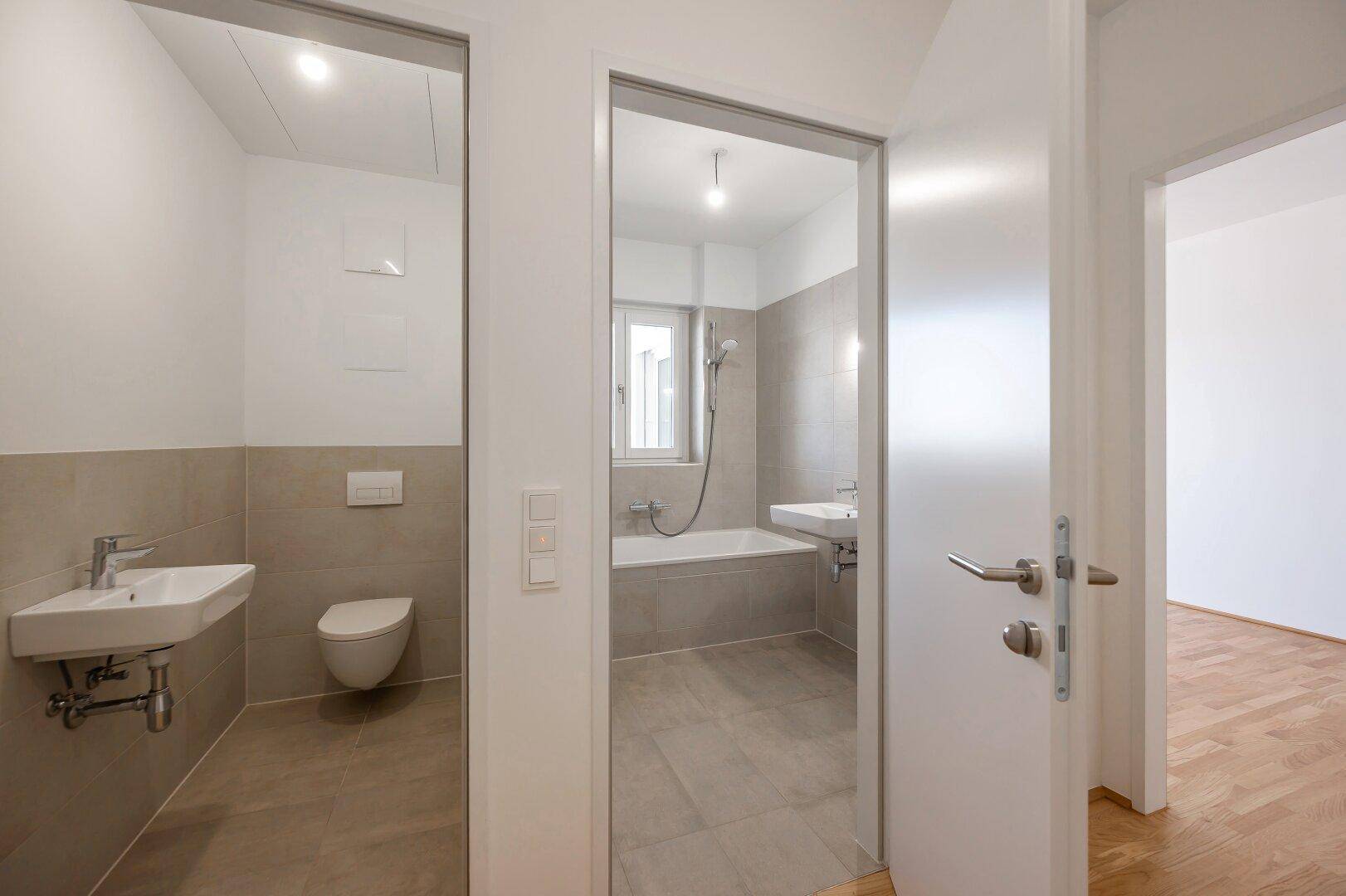 Modernes Badezimmer mit Badewanne, Waschbecken und separatem WC-Bereich.