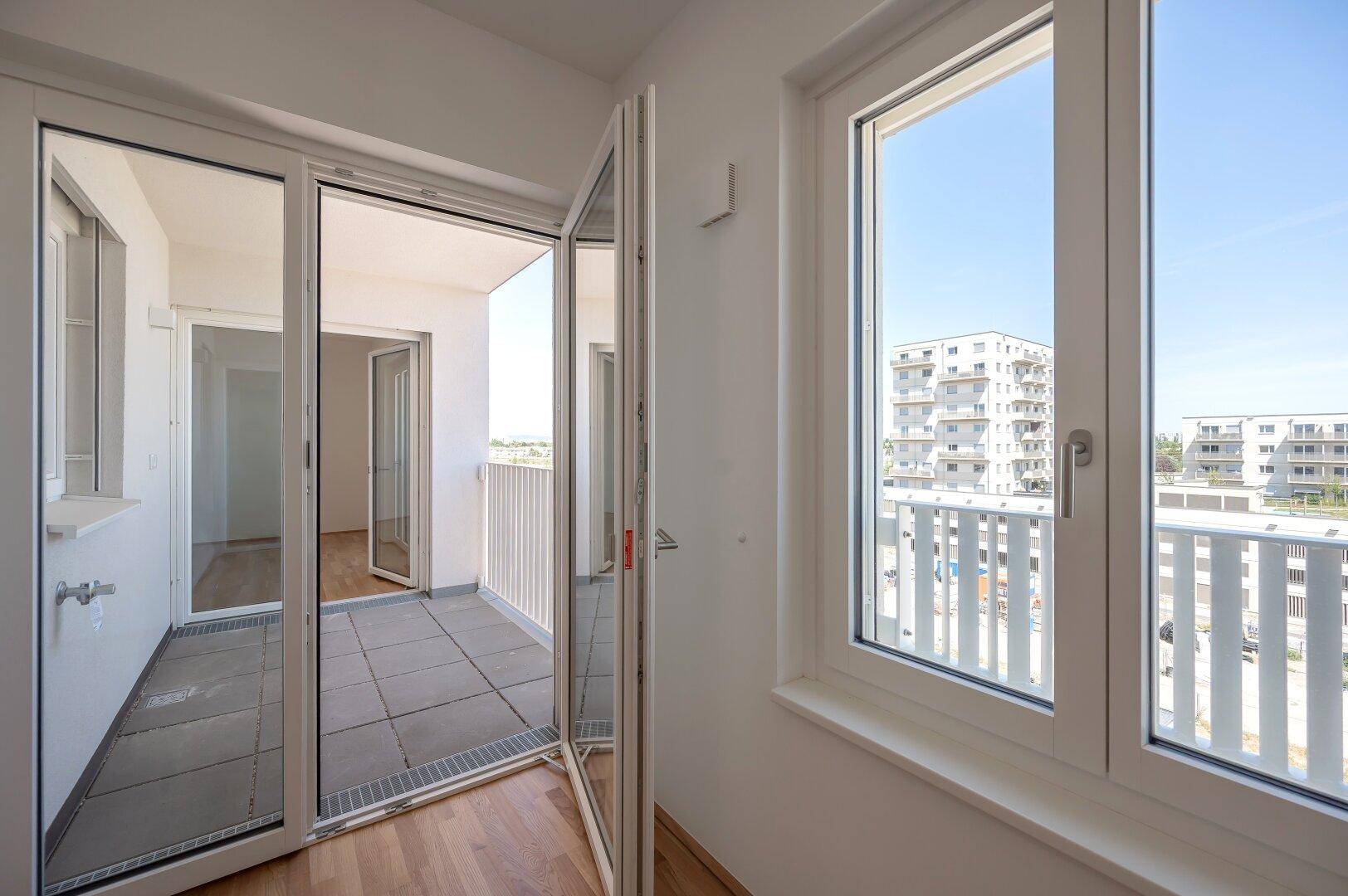 Große Fenster und Balkonzugang im Wohnbereich bieten weite Ausblicke und viel Helligkeit.